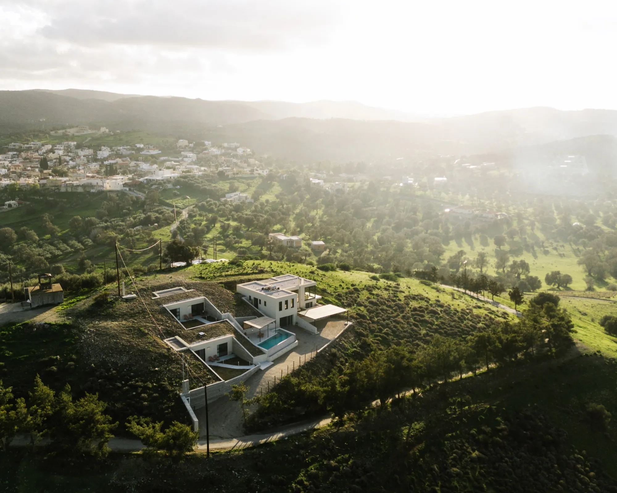 Aerial view of Hillside Crete's three houses built into a hilltop above Sivas village at golden hour